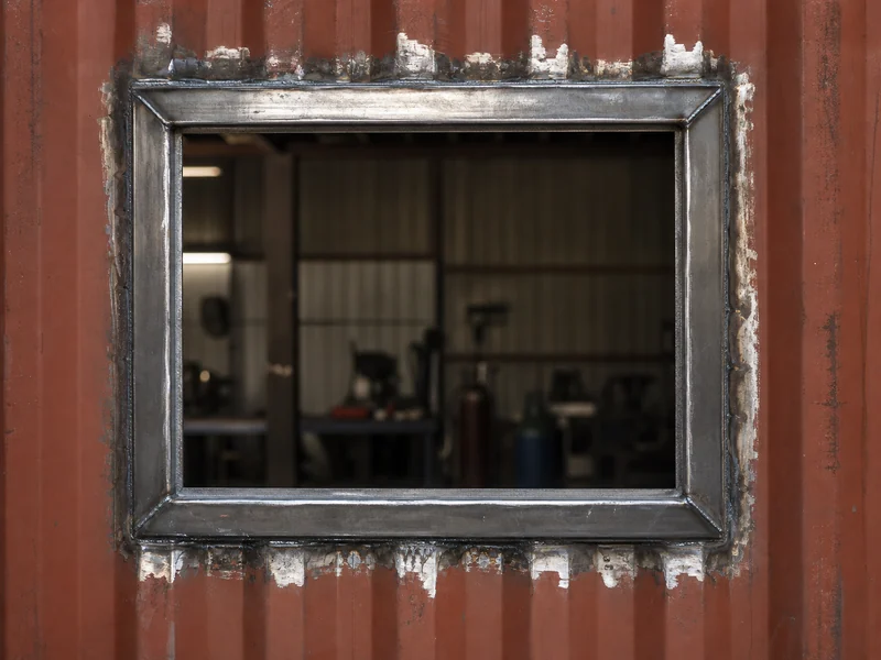 Reinforcement framing welded around a cut door opening in a shipping container side wall during a container building conversion