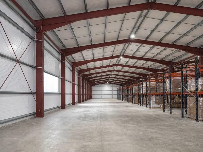 Interior clear span frame and sidewall bracing in a steel warehouse with racking between column lines